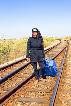 Young woman with her suitcase on a railroad track