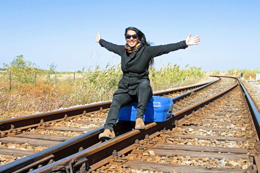 Young woman with her suitcase on a railroad track