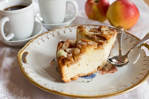 Closeup of a delicious baked apple cake, almonds and a cup of coffee.