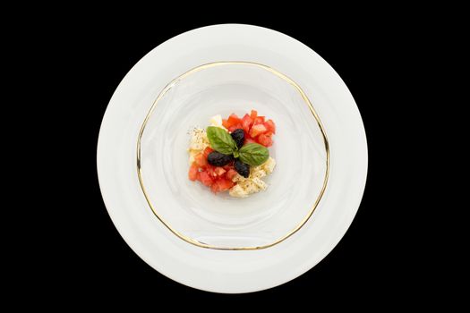 Delicious caprese tartar in glass plate on a black background.