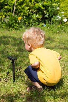 Little child interested by solar battery in his garden.