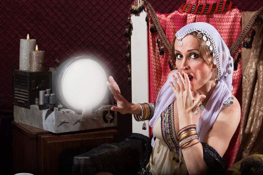 Startled sexy female fortune teller in headscarf