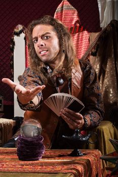 Handsome male fortune teller with tarot cards and crystal ball