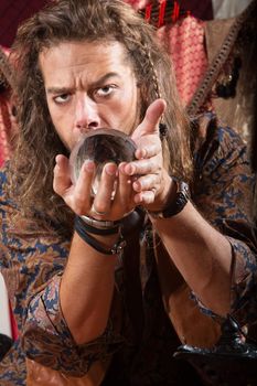 Serious Gypsy man coddling a crystal ball