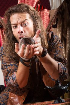 Surprised man holding crystal ball close to his face