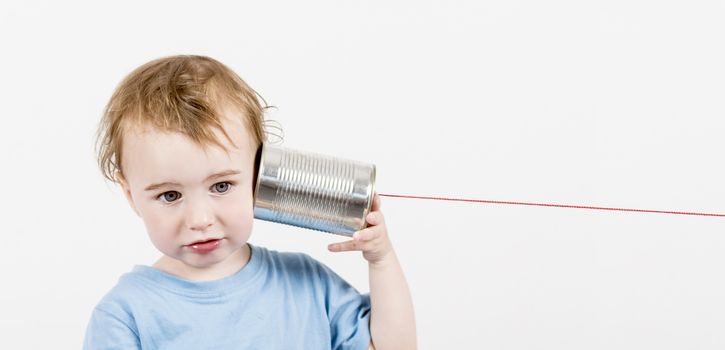 young, disappointed child listening to tin can phone. caucasian child in horizontal image