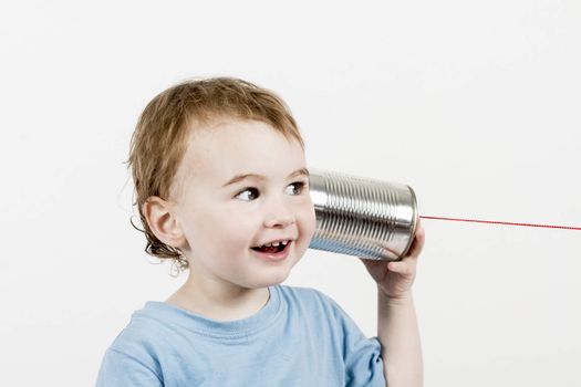 happy child in light grey background listening to tin can phone. horizontal image