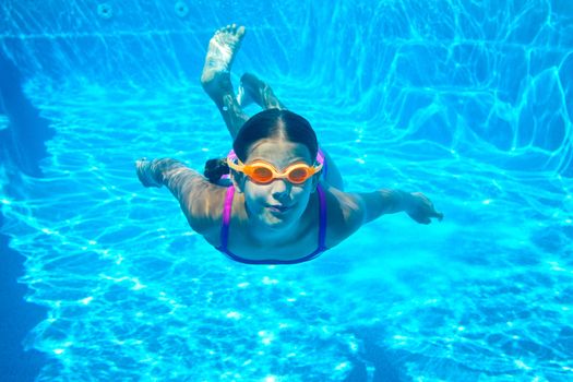The little girl in the water park swimming underwater and smiling