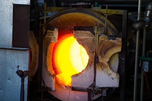 A very hot glassblowing furnace kiln is heating up ready for the molten glass.