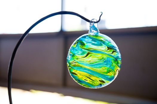 A unique one of a kind glass float was hand blown at a glassblowing studio in Oregon. The float hangs on a hook to show it off.