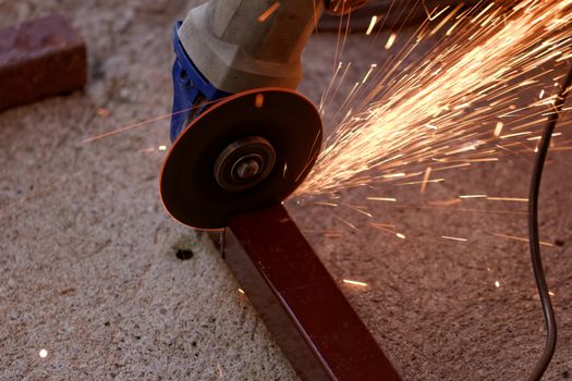 Metal sawing with hand grinder. Sparks while grinding iron.