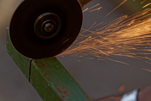 Metal sawing with hand grinder. Sparks while grinding iron.