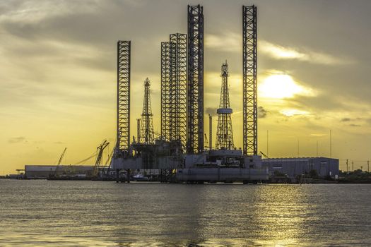 Sunset behind an oil and gas plant near the water.