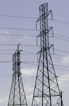 Dual power line towers set in front of a blue skyline