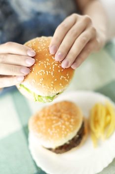 Woman holding humburger and sitting at the table