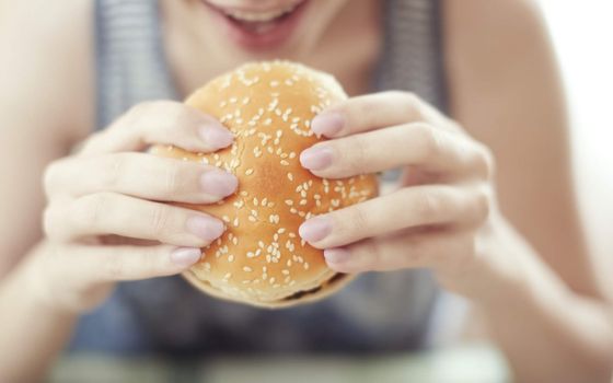 Woman holding and eating humburger