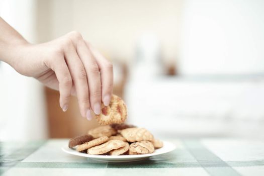 Human hand taking cookie in plate on a table