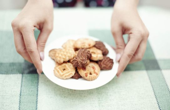 Human hands putting plate with cookies to the table