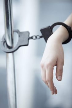 Human hand bounded to the metal pole by handcuffs