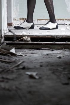 Human legs in stylish shoes standing in the ruined dirty room