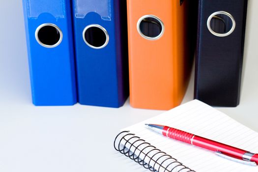 Colored file binders and pen on notes in office