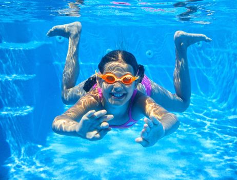 The cute girl swimming underwater and smiling