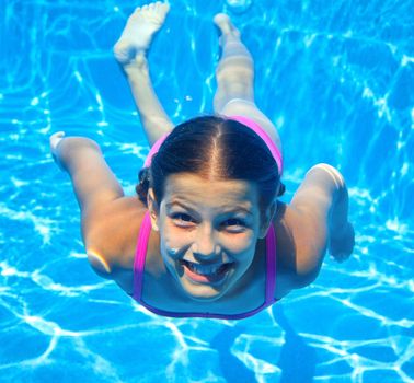 The cute girl swimming underwater and smiling