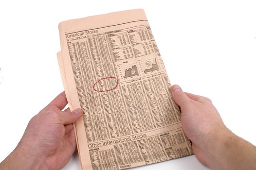 Male hands circle stock information in a newspaper against a white background.
