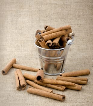 Aromatic cinnamon in small bucket on linen background