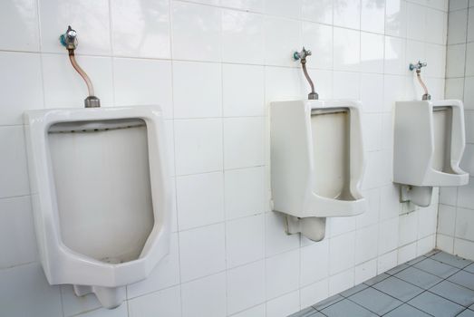 urinals on a marble tiled wall in a men's restroom 