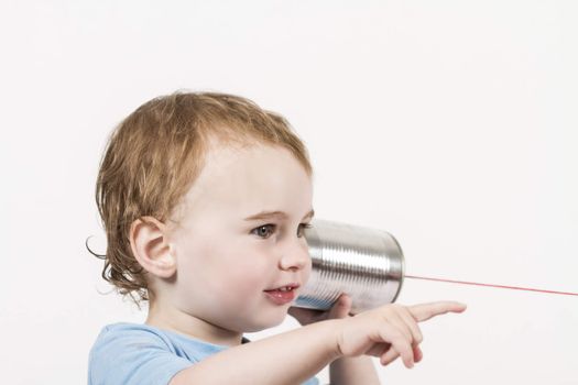 young, happy child listening to tin can phone and pointing at speaker caucasian child in horizontal image