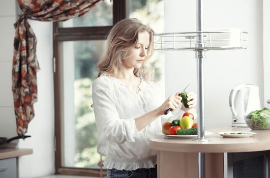 Blond lady at kitchen preparing vegetable for breakfast