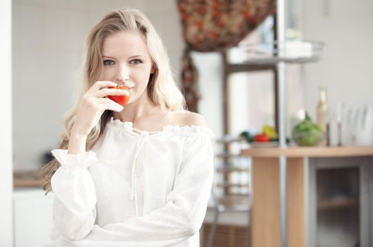 Blond lady with ripe tomato at the kitchen