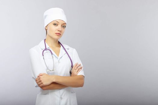 Cross-armed doctor with stethoscope on a gray background. Healthcare theme