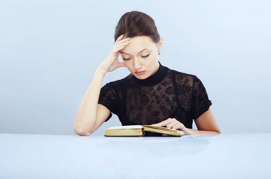 Lady at the table reading interesting book indoors