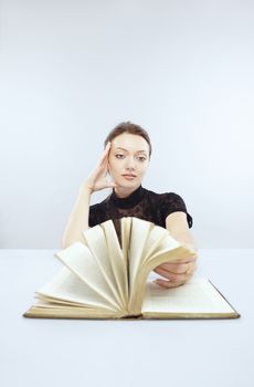 Smiling lady at the table reading the book with moving pages