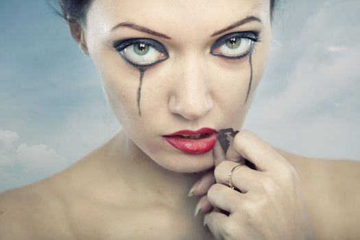 Portrait of the gothic lady holding razor and cutting lips. Special cross-processed colors added