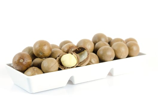  macadamia fruits  in  white bowl  on white background 
