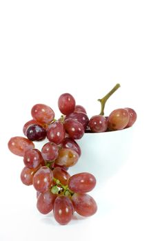 close up branch of red grape in white bowl on white background.