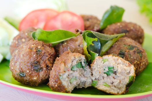 close up spicy meatballs served with fried  bergamot leaves and fresh vegetable 