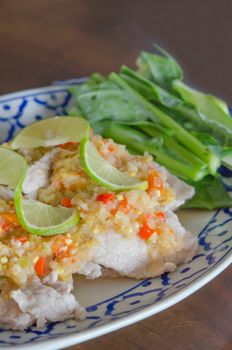 close up spicy pork served with chili sauce and fresh vegetable on dish