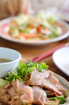 close up sliced grilled   pork  served with vegetable and chili sauce