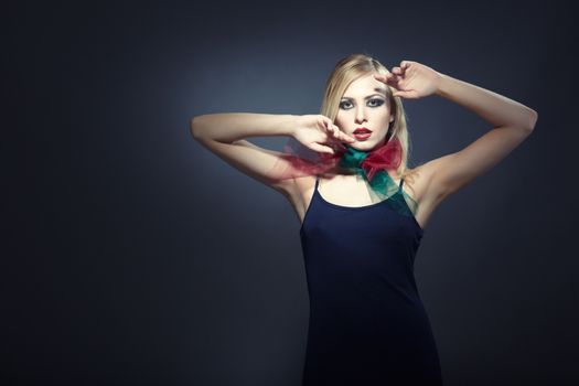 Elegant blond lady in stylish dress and colorful scarf posing in the studio on a dark background