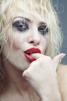 Sexy blond lady with bizarre makeup and finger in her mouth