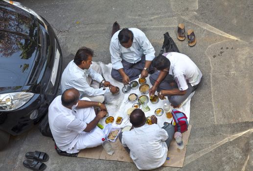 Ariel shot of Indian private car drivers having lunch in a public car park near their vehicles. Location of shot, Bombay India