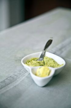 Vertical capture of a porcelain chin butter boat and knife on a white table cloth furniture with a table runnera