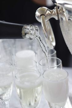 Pouring sparkling beverage on flute glasses