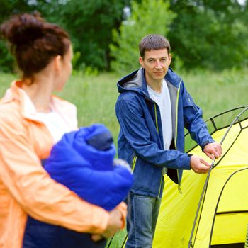 Young man camping near tent in park