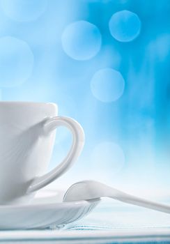 white ceramic cup with spoon on blurry blue background