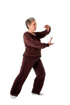 Beautiful Senior woman doing Tai Chi exercise to keep her joints flexible, isolated.